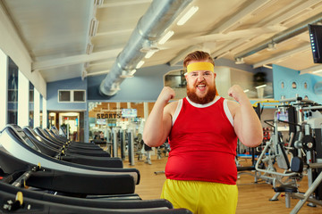 Fototapeta na wymiar A funny fat man with a beard doing exercises in the gym.