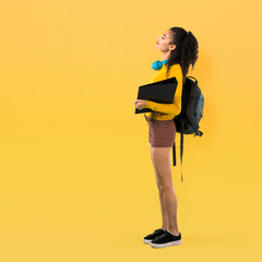 Full body of Teenager student girl with curly hair with back pain on yellow background