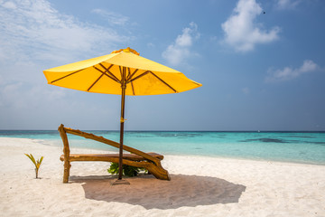 A sun lounger and a beach umbrella on a deserted beach; perfect vacation concept; blue sky; amazing sea
