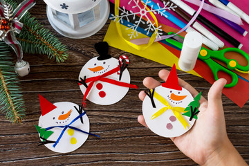 A child is holding Christmas snowman merry gift. Handmade. Project of children's creativity, handicrafts, crafts for kids.