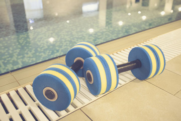 foam dumbbells for sports lie in the pool, the concept of a healthy lifestyle