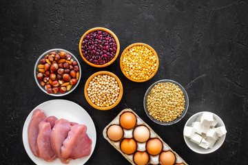 Food for sportsmen. Legumes, nuts, low-fat cheese, meet, eggs on black background top view copy...