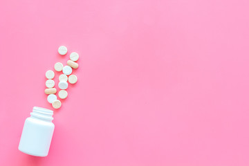Medicine. Pills falling out of jar on pink background top view copy space