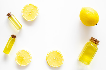 Natural cosmetics. Lemon essential oil near halfs os lemons on white background top view closeup...