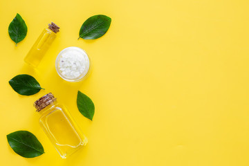 Natural hipoallergenic cosmetics with tea tree essential oil. Oil, lotion, leaves on yellow background top view copy space