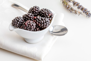 Delicious fresh blackberries and ripe black and reddish garnet. In white bowl and isolated background. With lavender, rosemary, lemon zest, mint and apricots.