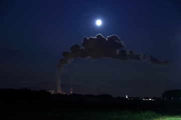 Elektrownia, fabryka w nocy w świetle księżyca w pełni nad chmurą pary.