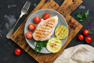 BBQ Chicken fillet with vegetables on a dark concrete background. Top view, overhead, flat lay.