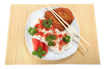 Ryż na białym talerzu z kotletem schabowym, sosem, pomidorem, zieloną petruszką i bazylią. - obrazy, fototapety, plakaty