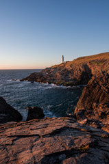 Fototapeta na wymiar Lighthouse on a rocky shore sunset