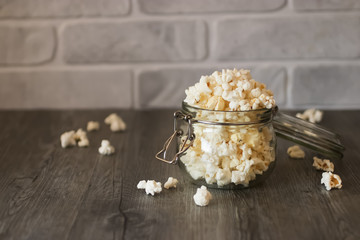 Popcorn in glass jar on gray background.