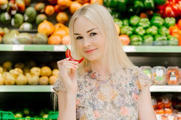 Attractive blonde nutritionist with chili pepper at supermarket