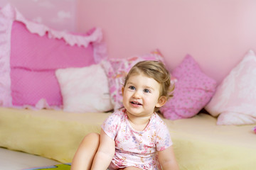 Fototapeta premium Happy Cute Baby Girl Sitting in her Pink Baby Room