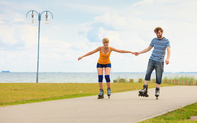 Young couple on roller skates riding outdoors