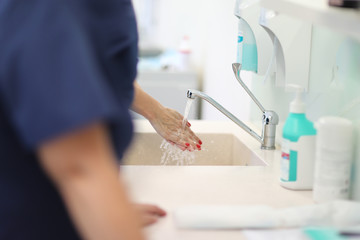 Woman doctor washes his hands before surgery under the spray.  running water