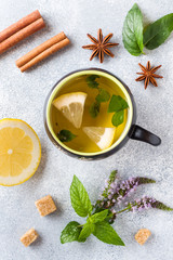 Obraz na płótnie Canvas Cup of tea, mint and lemon, brown sugar cinnamon and anise on a grey table