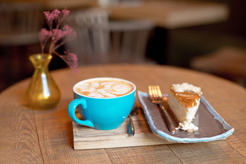 Blue coffee cup baked fruit pie on wooden tray over modern cafe iterior.