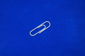 Eine weiße Briefklammer auf blauem Hintergrund