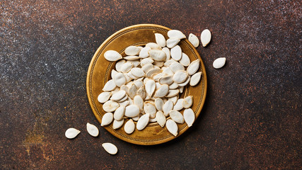 Raw pumpkins seeds on brown background with copy space. Top view.