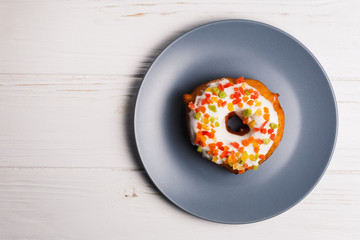 donut in sugar glaze with candied fruits on a blue plate