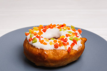 donut in sugar glaze with candied fruits on a blue plate