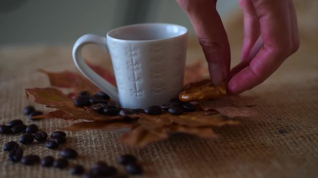 Cup of coffee espresso on saucer decorated autumn red maple leaves and coffee beans next to three pretzels on burlap surface. Rustic coffee during fall - autumn season concept. 