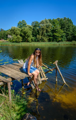 Fototapeta na wymiar Woman on the sea, the lake. Cute woman on a half-ruined wooden bridge over blue water on a sunny day