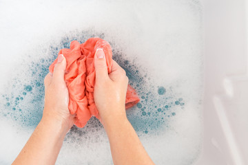 Female hands washing color clothes in sink