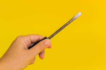 hand holding a screwdriver on a yellow background