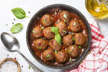 Meatballs in tomato sauce on white table.