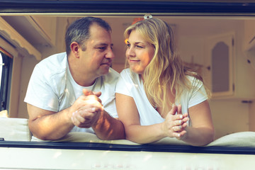 Happy couple of tourists sitting in a camper van.