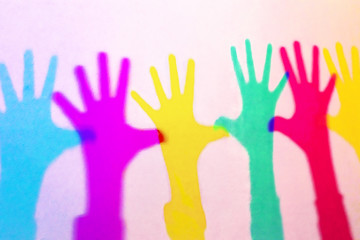 multicolored shadows of children's hands on a white wall