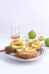 Fresh green figs Porcelain plate Wholegrain bread Honey Goat cheese Healthy eating concept Canapes Sandwiches Appetizer Copy space White background Vertical