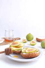 Fresh green figs Porcelain plate Wholegrain bread Honey Goat cheese Healthy eating concept Canapes Sandwiches Appetizer Copy space White background Vertical
