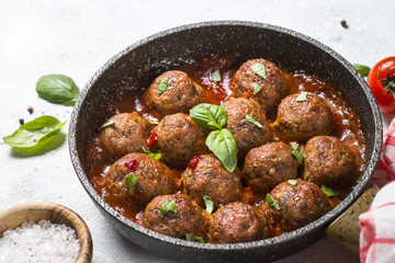 Meatballs in tomato sauce on white table.