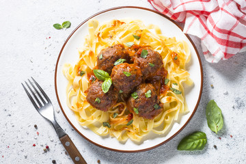 Meatballs in tomato sauce with pasta tagliatelle top view.