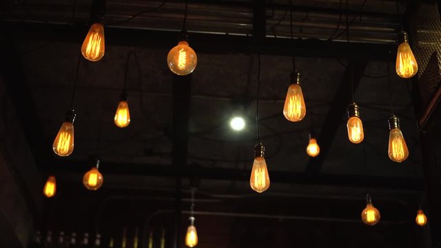 Vintage and retro yellow light bulb hanging over dark background in cafe at night.