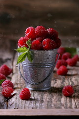 свежая малина в цинковом ведре с зелеными листьями