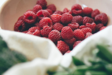 Fresh raspberries in the bowl with vegetable canvas bags. Processed filtered summer image