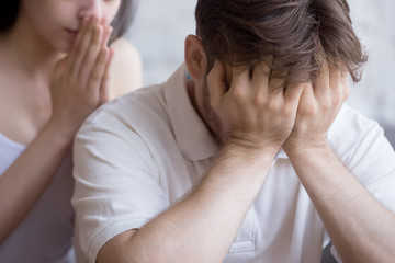 Fototapeta premium Upset millennial man feel desperate and down having problems at work or business, young girlfriend try to caress or show support, frustrated confused wife attempt to calm or comfort husband. Close up