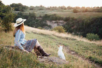 in autumn a girl in a hat is walking with a white dog