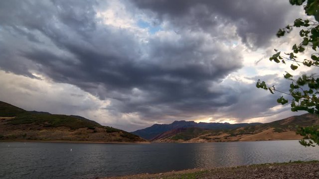 Time lapse of dramatic clouds moving over lake at sunset in Utah.