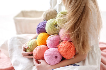 The beautiful girl with a smile and with multi-colored skeins of thread