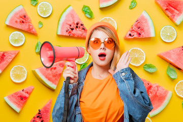 Young style girl in jeans clothes with pink megaphone on fruit background. Symbolizes female...