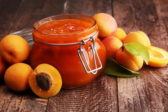 Jam from apricots in a glass jar on a wooden surface