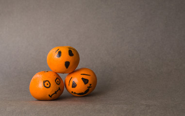 Horizontally dark background for Halloween with three tangerine pumpkins
