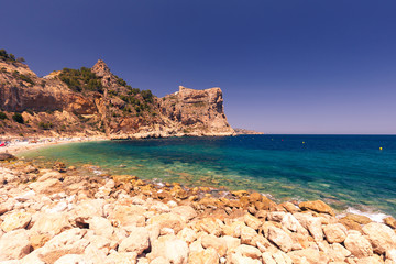 Beautiful view of beach in a bay with turquoise water at sunset, La playa Moraig in Cumbre del Sol, Spain.
