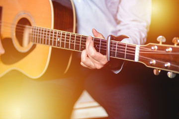 Fototapeta na wymiar Guitar with a man's male hands playing the guitar on wooden wall background, electric or acoustic guitar with nature light. Concept of guys boys band performing on events 