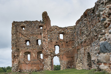 Fragment of a ruined stone wall with an arch and windows