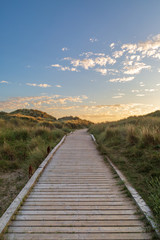 Fototapeta na wymiar A wooden pathway leading towards the sea at Formby in Merseyside, taken at sunset